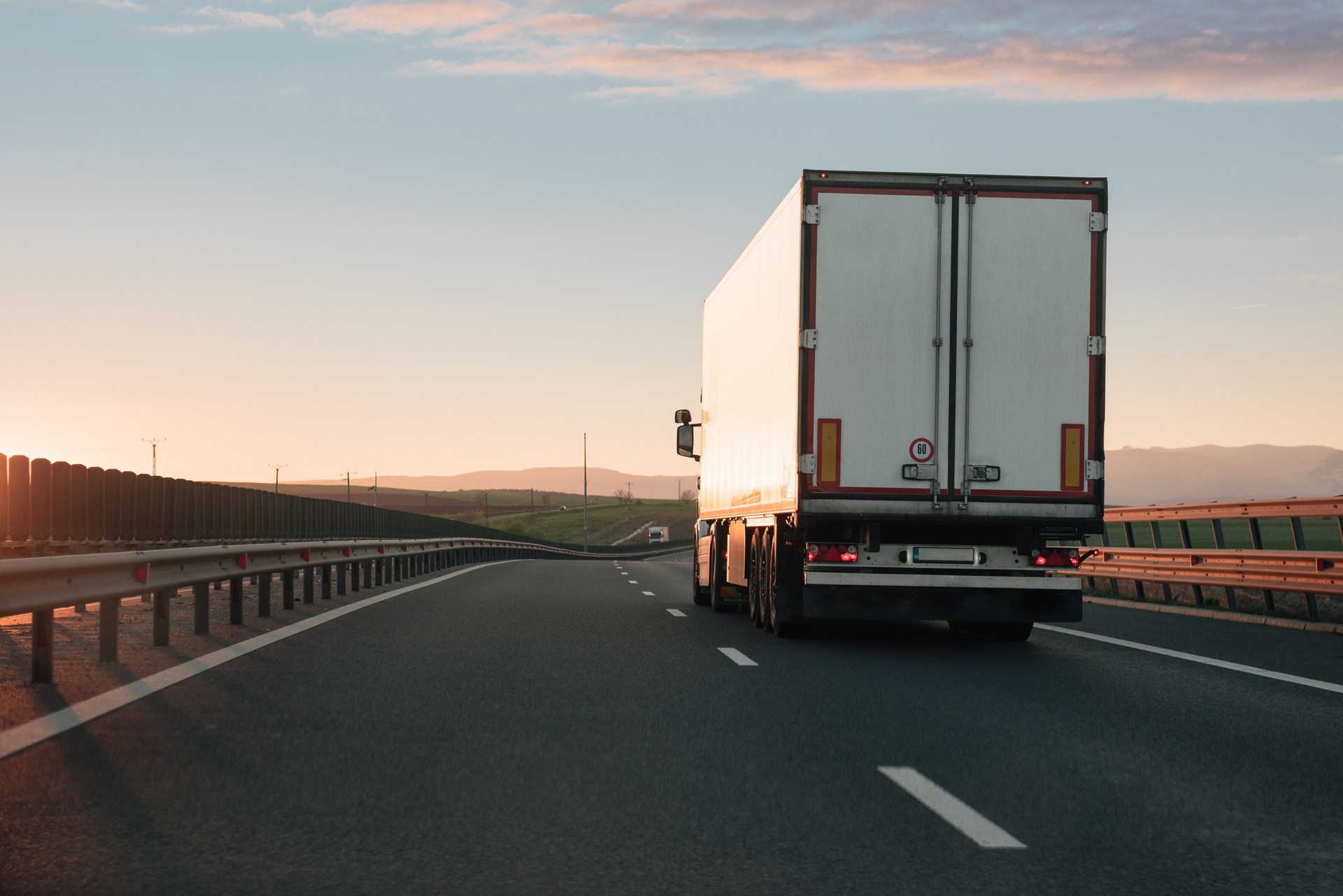 White truck driving on empty highway during sunset